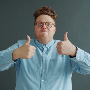 Man with glasses gives two thumbs up.